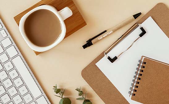 penne personalizzate e block notes con tazza di caffè su tavolo di legno